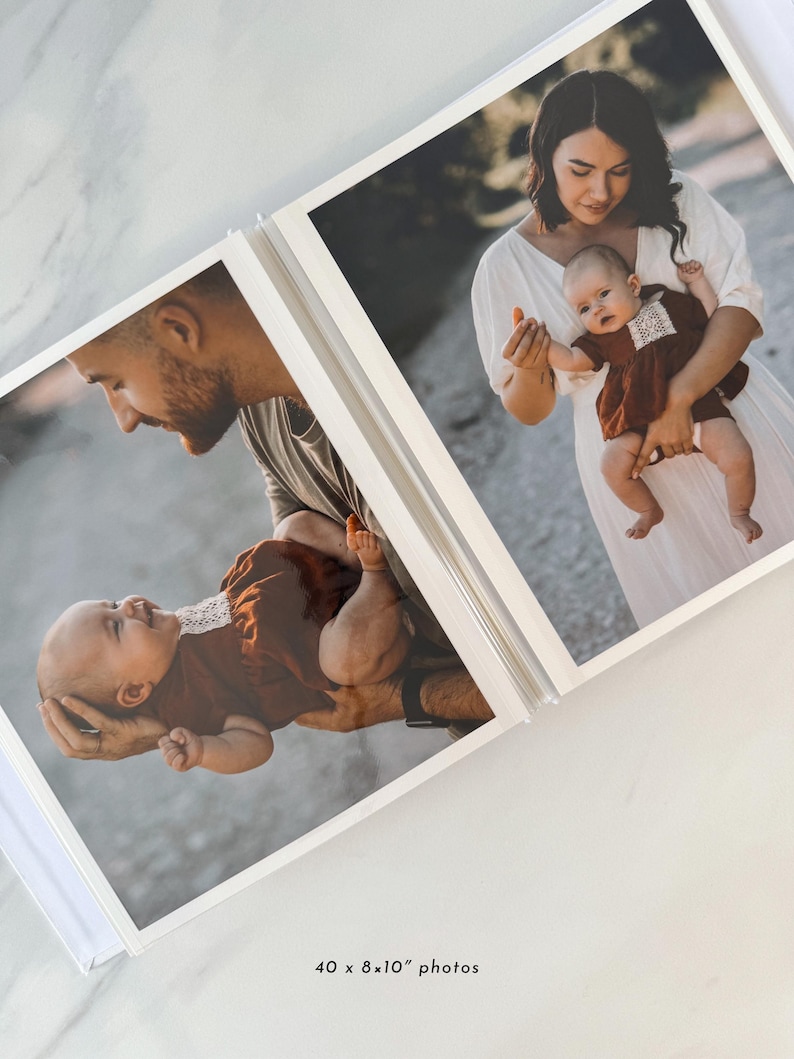 A photo album with two pages featuring a woman holding a baby, both smiling and looking at the camera.