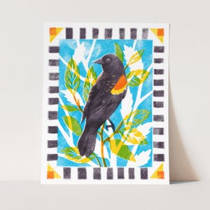May include: A black and red bird with a yellow beak perched on a branch with green and yellow leaves against a blue background. The bird is surrounded by a black and white border.
