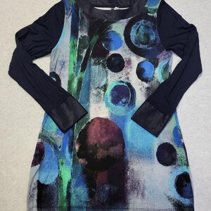 May include: A long-sleeved dress with an abstract design in blue, green, and purple circular patterns. The sleeves and neckline are navy blue, with faux leather cuffs. The dress has a scoop neckline. Measurements are in centimetres.