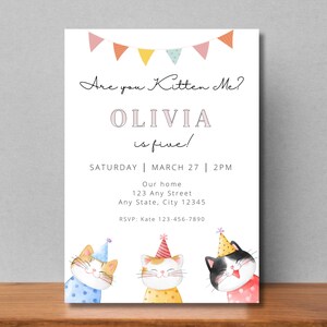 May include: A white invitation with a pink banner at the top. The text reads "Are you Kitten Me? Olivia is five!"  The invitation also includes the date and time of the party, the address, and an RSVP number. The bottom of the invitation features three cartoon cats wearing party hats.