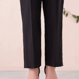May include: Black pants with a straight leg fit. The pants are cropped and end just above the ankle. The person is wearing black heeled sandals.