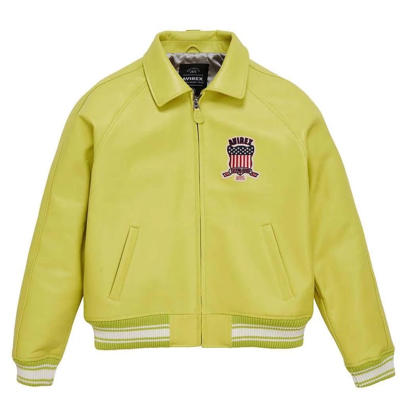 May include: A chartreuse leather jacket with a collared neckline and a zip closure. The jacket features a patch on the chest with the text "AVIREX" and an American flag design. The cuffs and hem have white and green striped detailing.