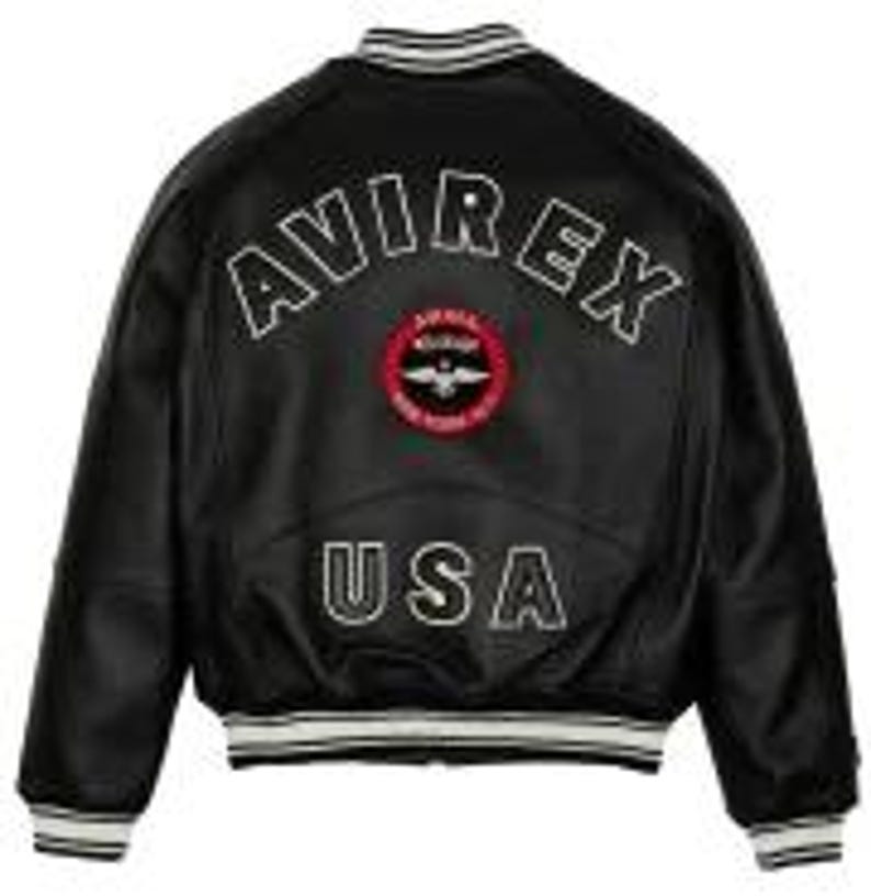May include: Black leather bomber jacket with white trim on the collar, cuffs, and hem. The back features the text "AVIREX" above a circular patch and "USA" below. The jacket has a classic, sporty design.