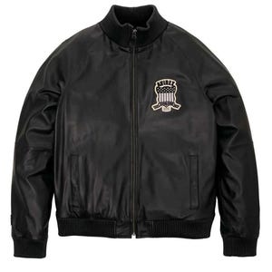 May include: Black leather jacket with a ribbed collar, cuffs, and hem. Features a full-length zipper and a patch on the chest with the text "AVIREX" and a shield design. A classic bomber jacket style.