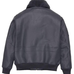 May include: A dark navy blue leather bomber jacket with a shearling collar. The jacket features a ribbed knit hem and cuffs, and a patch on the upper left sleeve. The back view shows the jacket's design details.