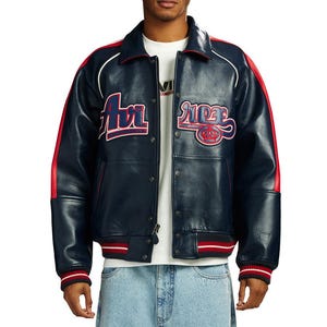 Puede incluir: Chaqueta de cuero azul marino con detalles rojos y blancos. La chaqueta presenta la palabra "Air" en rojo y azul en el pecho izquierdo y "ACE" con un emblema de corona en el derecho. Las mangas tienen rayas rojas.