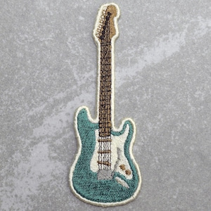 May include: An embroidered patch of a teal electric guitar with a brown neck and white pickguard.