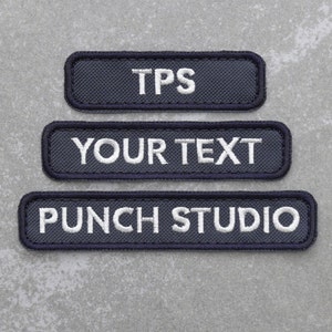 May include: Three dark blue fabric patches with white embroidered text. The top patch reads "TPS". The middle patch reads "YOUR TEXT". The bottom patch reads "PUNCHI STUDIO".