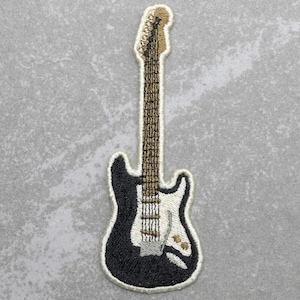 May include: Black and white embroidered electric guitar patch. The guitar has a white pickguard and a brown neck.