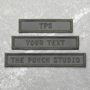 May include: Three grey fabric patches with green stitching. The top patch says "TP'S". The middle patch says "YOUR TEXT". The bottom patch says "THE PUNCH STUDIO".