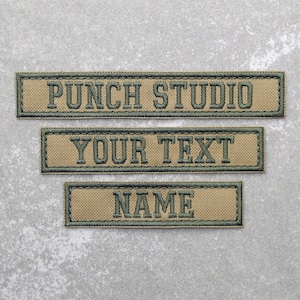 May include: Three tan fabric patches with green embroidered text. The top patch reads "PUNCH STUDIO", the middle patch reads "YOUR TEXT", and the bottom patch reads "NAME".