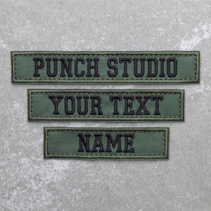 May include: Three green fabric patches with black embroidered text. The top patch reads "PUNCH STUDIO", the middle patch reads "YOUR TEXT", and the bottom patch reads "NAME".