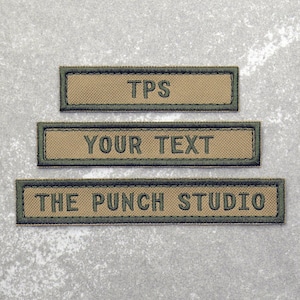 May include: Three tan fabric patches with green stitching. The top patch says "TPS". The middle patch says "YOUR TEXT". The bottom patch says "THE PUNCH STUDIO".