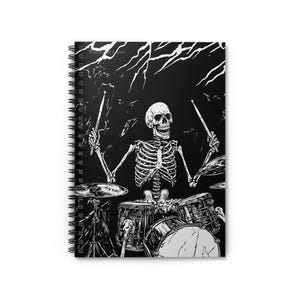 May include: Spiral-bound notebook featuring a black and white illustration of a skeleton playing a drum set. The skeleton is in the center, with drumsticks raised, and a black background with lightning.