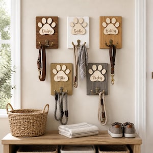 Puede incluir: Cinco soportes de madera para correas de mascotas montados en la pared con recortes de huellas. Cada placa tiene un nombre: Daisy, Sadie, Bailey, Milo y Rocky. Los soportes tienen ganchos dobles de tono bronce para colgar correas y accesorios.