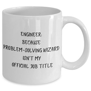 Könnte beinhalten: Weiße Keramik-Kaffeetasse mit schwarzem Text, der lautet: "Ingenieur: Weil Problemlöser-Zauberer nicht mein offizieller Jobtitel ist."