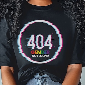 May include: A black t-shirt with a white circle graphic that says "404 Gender Not Found" in a rainbow glitch effect.