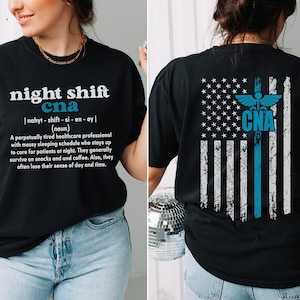 May include: Black t-shirt with a white graphic design that reads "night shift cna" and a definition of the term. The back of the shirt features a blue and white American flag with a medical caduceus symbol and the letters "CNA" in the center.