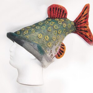 May include: A novelty fish-shaped hat in green, yellow, orange, and red felt. The hat has detailed fins and scales, and is displayed on a white mannequin head. The hat's design is eye-catching and unique.