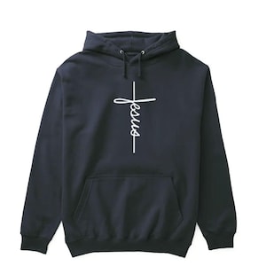 Peut inclure: Un sweat à capuche bleu marine avec une croix blanche et le mot "Jésus" écrit verticalement dessus.