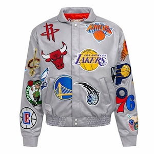 Pode incluir: Um blusão bomber de cetim cinza-claro com vários logotipos de equipas da NBA e gráficos de basquetebol bordados na frente e nas mangas. O casaco tem um fecho de botões de pressão, bainha canelada e um forro vermelho vivo no interior.