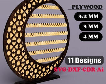 May include: A dark brown wooden earring display with a crescent moon shape, featuring heart cutouts and multiple rows of earring slots. The text "EARRING DISPLAY", "PLYWOOD", "11 Designs", and "DIGITAL DOWNLOAD" are visible.