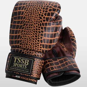 May include: A pair of brown leather boxing gloves with a crocodile pattern. The gloves have black accents and the text "TSSB SPORTS" and "www.tssbsports.com" on the wrist strap.