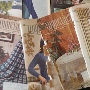 May include: A collection of vintage The Workbasket and Home Arts magazines featuring various cover illustrations of people, home decor, and craft projects. The magazines display titles, volume numbers, and dates, with colorful photography and graphic designs.