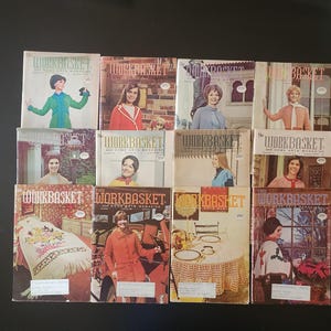 May include: A collection of vintage "Workbasket" magazines, featuring colorful covers with images of women and home decor. The magazines showcase various crafts and home arts, with a retro aesthetic. The covers display the magazine title and issue numbers.