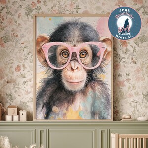 Può includere: Una stampa ad acquerello incorniciata di uno scimpanzé con occhiali rosa. Lo scimpanzé ha la pelliccia scura e un'espressione sorridente. Lo sfondo presenta schizzi di acquerello gialli, rosa e blu.