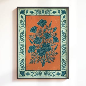 Könnte beinhalten: Ein gerahmter rechteckiger Kunstdruck mit einem zentralen Blumenstrauß aus dunkel-türkisfarbenen Blüten und Knospen auf einem rostorangen Hintergrund. Das Bild ist von einem hellen mintgrünen Rand mit einem Blattmuster umgeben.
