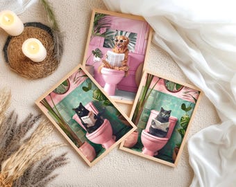 May include: Three framed art prints featuring animals on toilets. One print shows a golden retriever wearing sunglasses and reading a newspaper. The other two prints depict black cats reading newspapers while sitting on pink toilets.