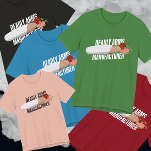 May include: A collection of short-sleeved t-shirts in various colors, including black, blue, green, pink, and red. Each shirt features the text "DEADLY ARMS MANUFACTURER" with a graphic of a white and brown object and floral accents.