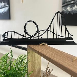 Könnte beinhalten: Schwarze Metall-Achterbahn-Skulptur mit Schlaufen und Hügeln. Das dekorative Stück ist auf einem schwarzen Sockel montiert und so konzipiert, dass es aufrecht steht. Ein einzigartiger Einrichtungsgegenstand.