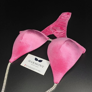 May include: Pink bikini top with a crystal chain strap. The top has a sweetheart neckline and a low back. The brand name "HARMONY BIKINI SHOP" is printed on a white card.