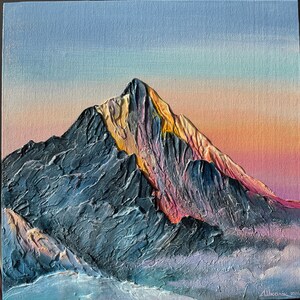 May include: Textured oil painting of a mountain range at sunset. The mountain is a dark gray with yellow and pink highlights. The sky transitions from light blue to orange and pink. The painting is signed in the bottom right corner.