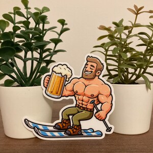 Puede incluir: Una pegatina de dibujos animados de un hombre musculoso esquiando mientras sostiene una cerveza. El hombre lleva pantalones verdes, botas de esquí marrones y un sombrero marrón. Los esquís son azules y blancos.