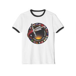 Puede incluir: Camiseta blanca con ribete negro que presenta un gráfico circular. El gráfico incluye un cohete, un sol naciente y el texto "PROJECT HAIL MARY" con banderas. Una camiseta elegante para los fanáticos de la ciencia ficción.