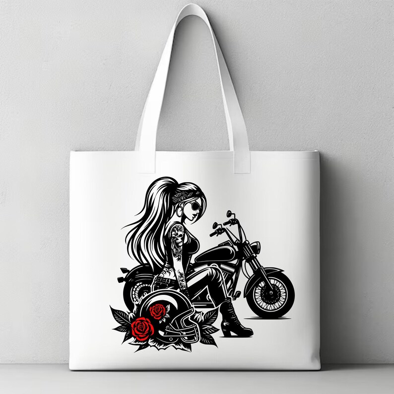 May include: A white tote bag with a black and white illustration of a woman riding a motorcycle. The woman is wearing a bandana, sunglasses, and a leather jacket. She is holding a helmet in her left hand. There are red roses on the ground near the motorcycle.