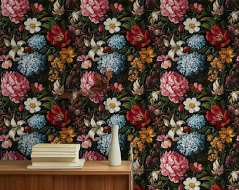 Può includere: Un design di carta da parati floreale scuro con una varietà di fiori nei toni del rosso, rosa, blu, giallo e bianco. I fiori sono fittamente raggruppati su uno sfondo scuro. Un tavolo di legno contiene una pila di libri e un vaso bianco.