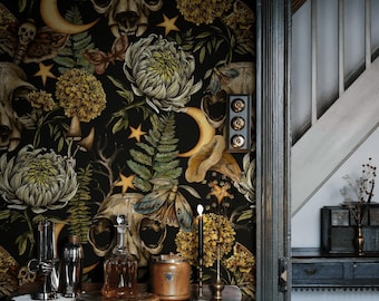 May include: A dark wallpaper featuring a repeating pattern of animal skulls, yellow chrysanthemums, green ferns, moths, and crescent moons on a black background. A wooden table sits in front of the wall with a glass decanter and metal canisters.