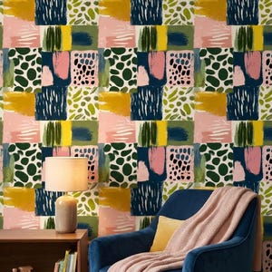 Peut inclure: Papier peint à motifs abstraits avec un motif en grille de blocs de couleurs. Le motif comprend des coups de pinceau et des formes roses, vertes, jaunes et bleu marine. Un fauteuil bleu en velours avec une couverture rose et un coussin jaune.
