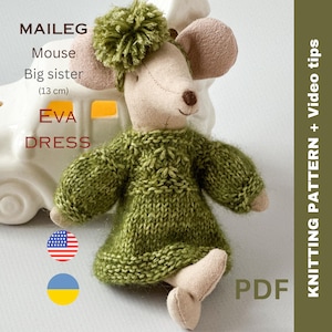 May include: A handmade stuffed mouse toy, approximately 5 inches tall, wearing a green knitted dress and a matching pom-pom hat. The text on the image reads "MAILEG Mouse Big sister (13 cm) EVA DRESS KNITTING PATTERN + Video tips PDF".