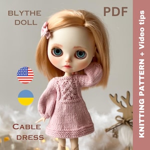 May include: A pink knitted cable dress for a Blythe doll. The dress has a cable knit pattern on the front and a plain knit on the sleeves and bottom. The doll is wearing the dress and has blonde hair and blue eyes. The image also includes the text "Blythe Doll", "Cable Dress", "PDF", "Knitting Pattern + Video Tips", and the flags of the United States and Ukraine.