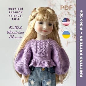 Könnte beinhalten: Strickanleitung für eine lila gestrickte Bluse für eine Puppe. Das Muster enthält eine PDF-Datei und Videoanleitungen. Das Muster ist in Englisch und Ukrainisch verfügbar.