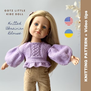May include: A purple knitted blouse with a cable knit pattern and puffed sleeves. The blouse is designed for a Gotz Little Kidz doll. The image includes the text "Knitted Ukrainian Blouse" and the flags of the United States and Ukraine.