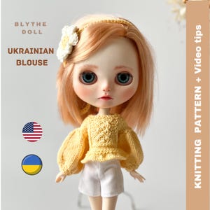 May include: A yellow knitted blouse with puffed sleeves for a Blythe doll. The doll is wearing the blouse and white shorts. The image includes the text "Blythe Doll", "Ukrainian Blouse", and "Knitting Pattern + Video Tips".