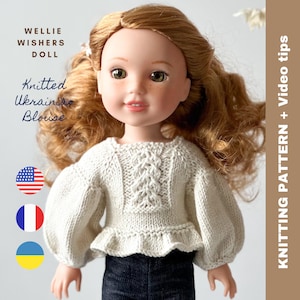 May include: A knitted white doll blouse with a cable knit pattern and a ruffled hem. The doll is wearing blue jeans. The image includes the text "Knitted Ukrainian Blouse" and the flags of the United States, France, and Ukraine.