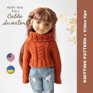 Può includere: Una bambola che indossa un maglione di lana arancione a treccia con collo alto. La bambola ha i capelli castani e gli occhi azzurri. Il maglione è di stile corto e la bambola indossa jeans blu. L'immagine include il testo "Ruby Red Doll Cable Sweater" e il testo "Knitting Pattern + Video Tips".