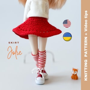 May include: A red crochet skirt for a doll, with the words "SKIRT Jolie" printed on the image. The doll is wearing white socks with red stripes and white sneakers. The image also includes the American and Ukrainian flags.